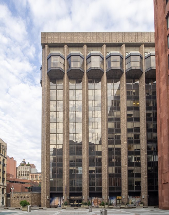 Exterior of the meeting venue, a tall building with stone columns and glass bay windows